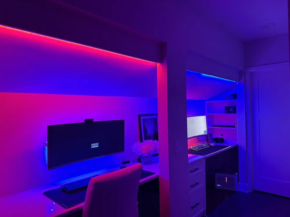 A TV and computer in a room with colorful accent lighting